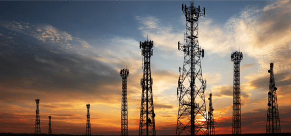 Silhouetted 5G cell towers at sunset. Powering business communication.