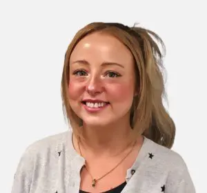 Katie Martin smiles, wearing a grey cardigan with black stars and a gold necklace.