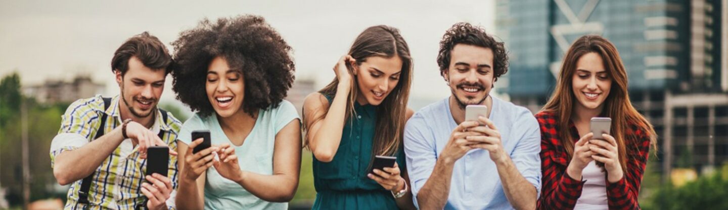 Group of young adults using smartphones, enjoying urban scene.