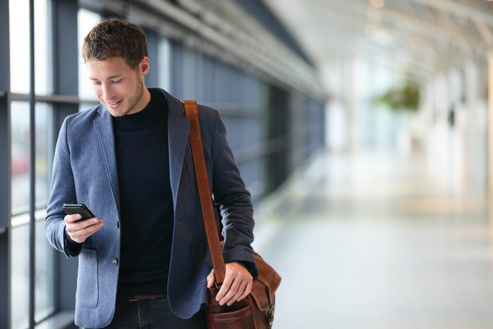 Man,On,Smart,Phone,-,Young,Business,Man,In,Airport.