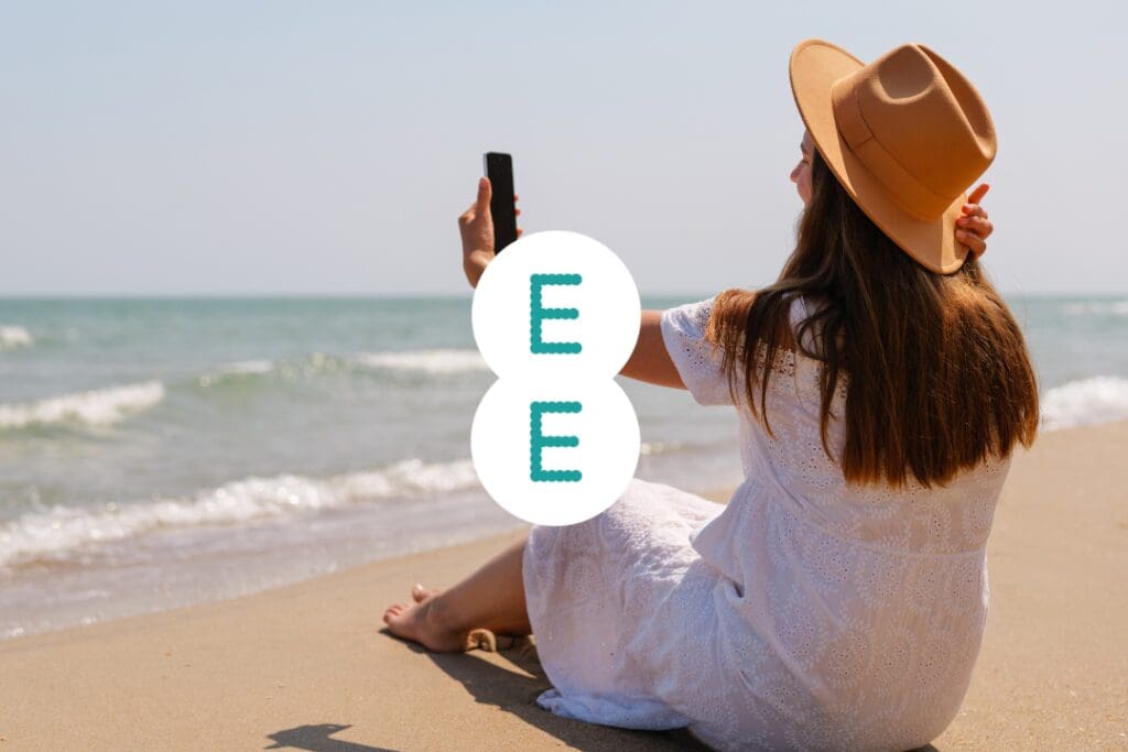 EE Roaming - Woman in a white dress and hat takes a selfie on a beach, with the letter E superimposed.